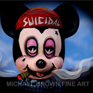 May include: A hand-painted figurine of Mickey Mouse wearing a red hat with the word "SUICIDAL" written on it. He has pink eyelids and is smoking a cigar. The background is a blue sky with white clouds.