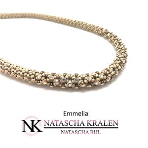 May include: A beige and white beaded necklace with a crystal embellishment. The necklace is called "Emmelia" and is made by Natascha Kralen.