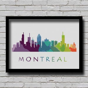 May include: A framed cross-stitch art piece featuring the Montreal skyline in a gradient of colors. The city's silhouette is rendered in shades of purple, blue, green, and orange. The word "MONTREAL" is stitched below the skyline.
