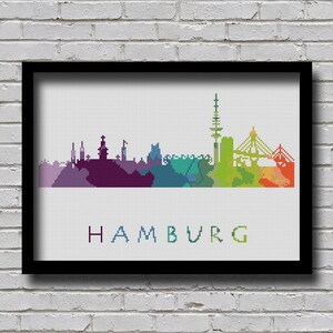 May include: A colorful pixelated cityscape of Hamburg, Germany. The skyline is rendered in a rainbow gradient, with purple, blue, green, yellow, orange, and red hues. The city name "HAMBURG" is written in blue below the skyline.
