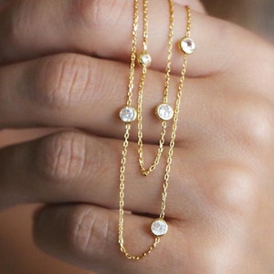 Hand holding a diamond station necklace with sparkling CZ diamonds, close-up shot highlighting the brilliance and shine of the stones.