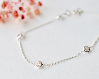 Peut inclure: Un bracelet délicat en argent avec quatre petites pierres claires.
