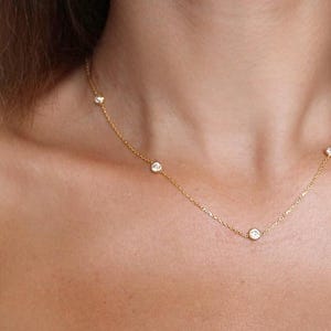 Diamond station necklace worn around the neck, showcasing the elegant design and how the CZ diamonds sparkle when worn.