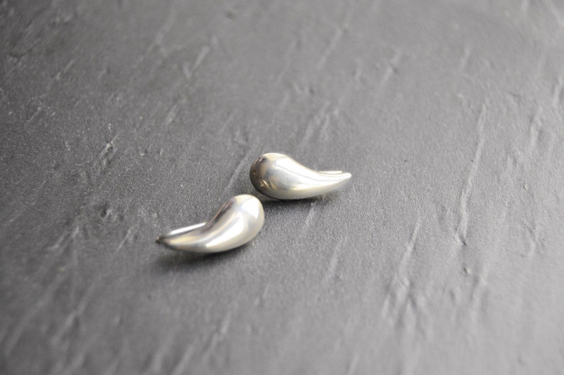 May include: A pair of silver teardrop-shaped earrings. The earrings are smooth and have a polished finish.