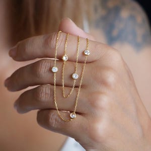 Hand holding a CZ diamond station necklace, focusing on the shimmering stones and elegant design in a close-up view.