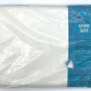 Puede incluir: Una s&aacute;bana de muselina blanca sin plancha en un paquete de pl&aacute;stico. El paquete tiene una etiqueta azul con el texto "Gnome No Iron Muslin Sheet" y detalles sobre las caracter&iacute;sticas y las instrucciones de cuidado de la s&aacute;bana. La etiqueta tambi&eacute;n incluye una gu&iacute;a de compra para diferentes tama&ntilde;os de s&aacute;banas.