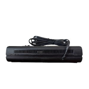 Puede incluir: Un dispositivo electr&oacute;nico negro con una serie de ranuras horizontales y un cable de alimentaci&oacute;n negro. El dispositivo rectangular parece ser un componente de un sistema electr&oacute;nico m&aacute;s grande. El cable de alimentaci&oacute;n est&aacute; enrollado encima del dispositivo.