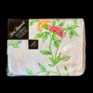 May include: A packaged twin fitted sheet set. The white sheet features a floral design with red, orange, and pink flowers, green leaves, and stems. The packaging reads "Lady Pepperell NO-IRON MUSLIN".