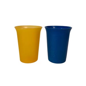以下が含まれることがあります： 2つのプラスチック製のコップ。1つは黄色、もう1つは青色です。どちらのコップも、わずかに広がった縁と滑らかでマットな仕上がりです。コップは空で、白い背景に置かれています。