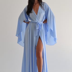 The model is wearing a long flowing silk robe with long wide sleeves.