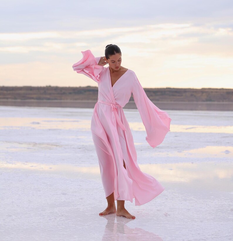 The model is wearing a long flowing silk robe with long wide sleeves.