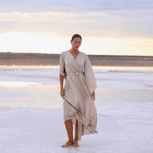 The model is wearing a long flowing silk robe with long wide sleeves.