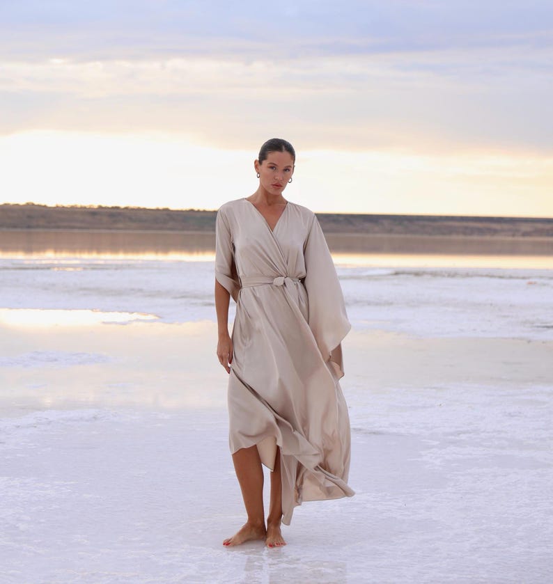 The model is wearing a long flowing silk robe with long wide sleeves.