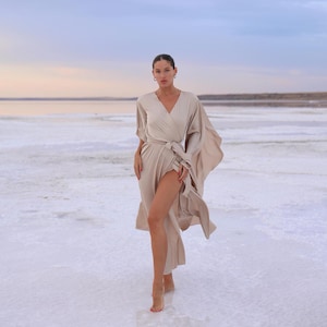 The model is wearing a long flowing silk robe with long wide sleeves.
