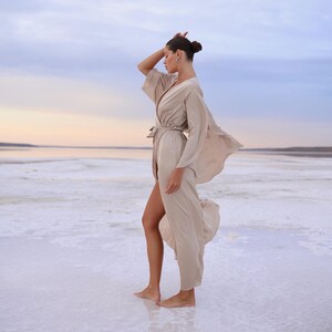 The model is wearing a long flowing silk robe with long wide sleeves.