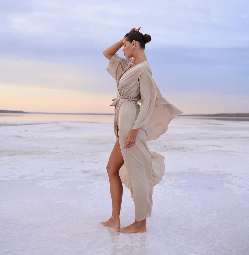 The model is wearing a long flowing silk robe with long wide sleeves.