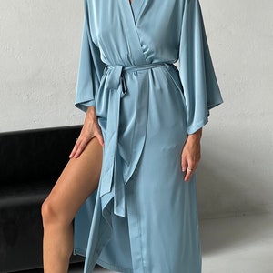 May include: A light blue satin robe with long sleeves and a tie belt. The robe is open in the front, revealing the person's legs.