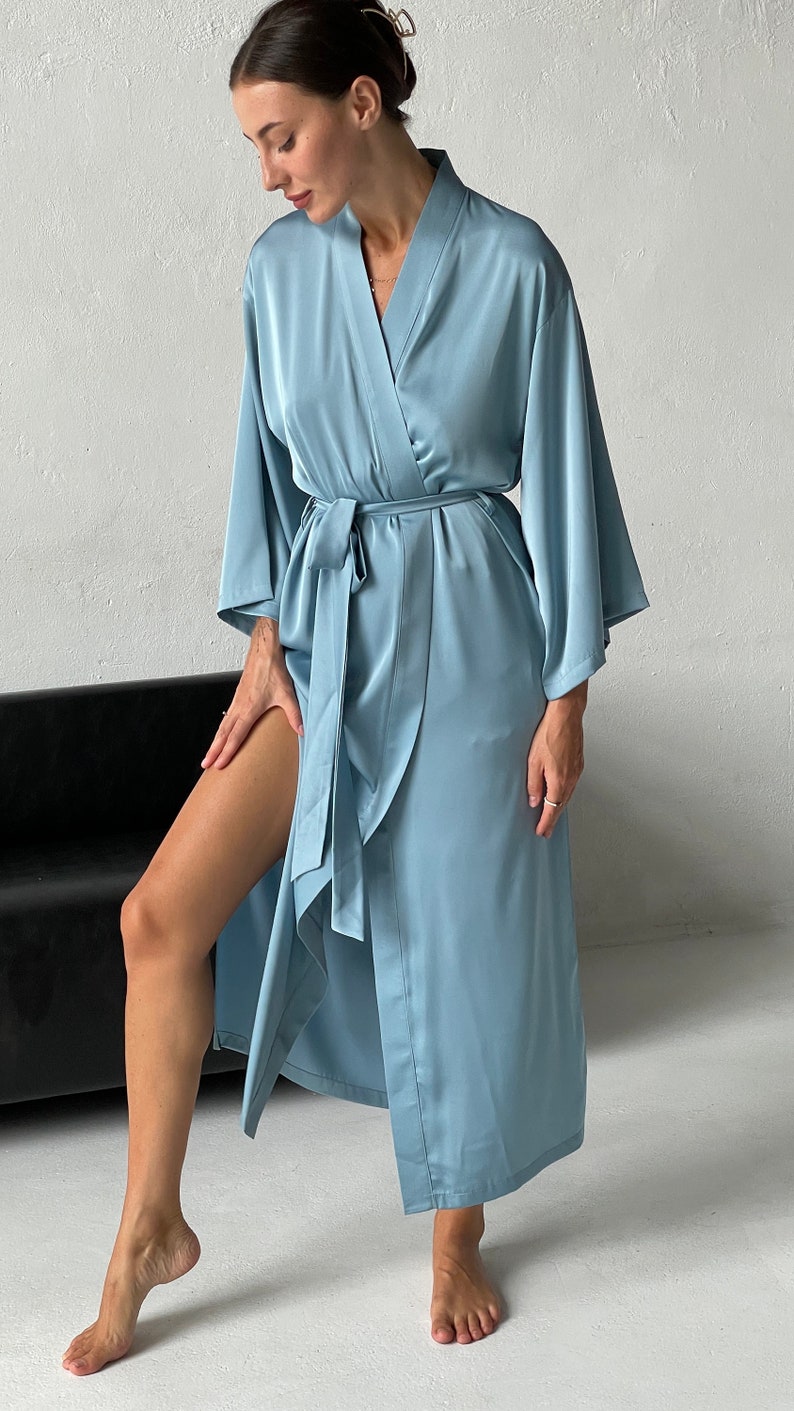 May include: A light blue satin robe with long sleeves and a tie belt. The robe is open in the front, revealing the person's legs.