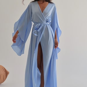The model is wearing a long flowing silk robe with long wide sleeves.