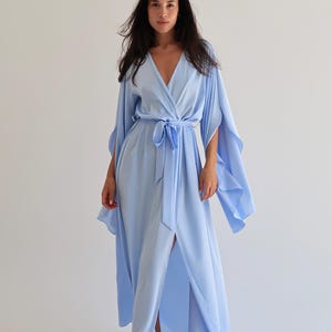 The model is wearing a long flowing silk robe with long wide sleeves.
