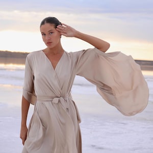 The model is wearing a long flowing silk robe with long wide sleeves.