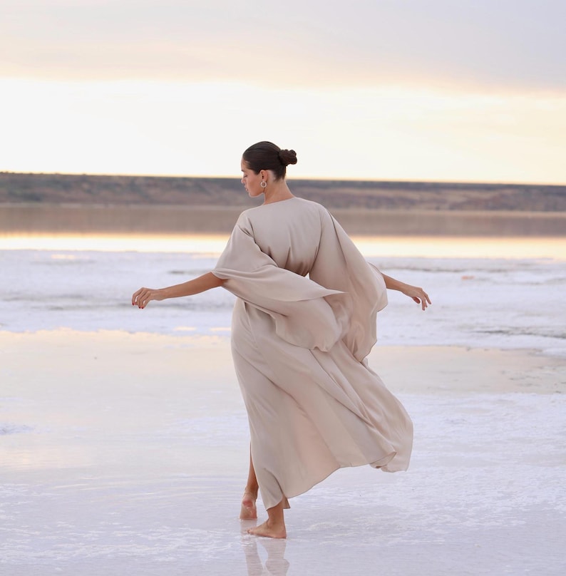 The model is wearing a long flowing silk robe with long wide sleeves.