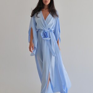 The model is wearing a long flowing silk robe with long wide sleeves.