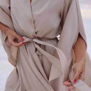The model is wearing a long flowing silk robe with long wide sleeves.
