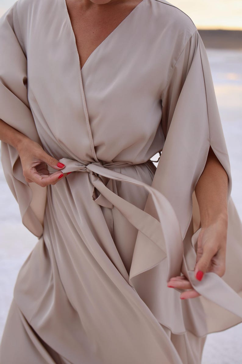 The model is wearing a long flowing silk robe with long wide sleeves.