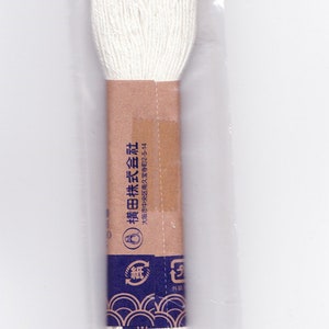 May include: A white spool of thread packaged in a clear plastic bag with a brown and blue label. The label reads "Yokota Co., Ltd." and "刺し子糸 (細)" which translates to "Sashiko Thread (Fine)".