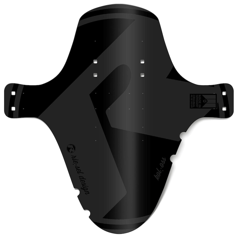 May include: Black bicycle fender with a geometric design. The fender has a wide, curved shape with two side extensions and multiple mounting holes. The text "riesel design" and "kol:ass" are printed on the fender. The fender is made in Germany.