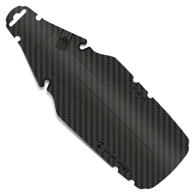 May include: A black carbon fiber bicycle mudguard with a textured weave pattern. The mudguard has a unique bottle shape with cutouts and the text "riesel design" and "nib-pe-l". The top has a hole for hanging.