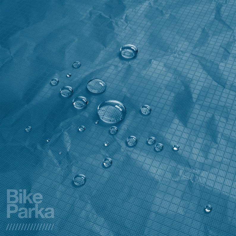 May include: Close-up of a teal blue, water-resistant fabric with several water droplets on the surface. The fabric has a grid-like pattern. The words "Bike Parka" are printed in white on the lower left.