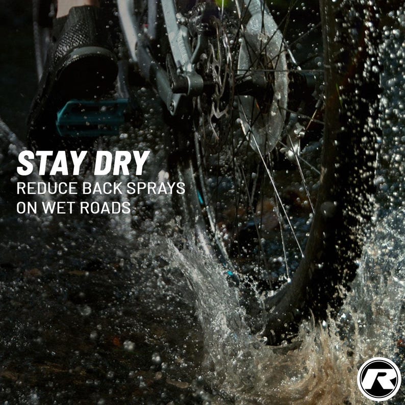 May include: A close-up shot of a bicycle wheel splashing through water. The image features the text "STAY DRY, REDUCE BACK SPRAYS ON WET ROADS." The wheel is black and silver, with water droplets and spray visible.