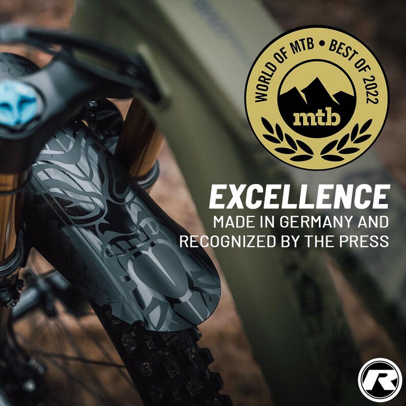May include: Close-up of a mountain bike with a black and gray front fender featuring a decorative pattern. The image includes a gold emblem that reads "WORLD OF MTB BEST OF 2022." Text on the image states "EXCELLENCE MADE IN GERMANY AND RECOGNIZED BY THE PRESS."