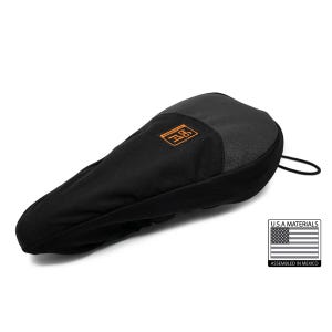 May include: Black bicycle seat cover with a textured top and a smooth, rounded shape. An orange square logo is visible on the top. A black drawstring is attached. The cover is made with U.S.A. materials and assembled in Mexico.