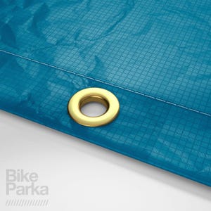 May include: Close-up of a section of a teal blue fabric with a grid pattern. A gold-colored grommet is set into the fabric. White stitching is visible along the edge. The text "Bike Parka" is in the lower left corner.