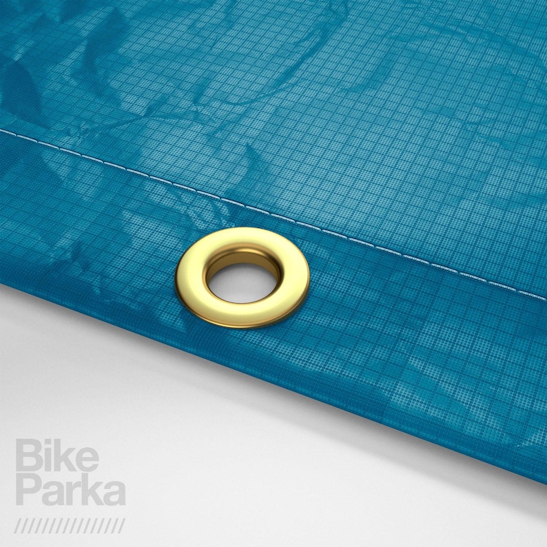 May include: Close-up of a section of a teal blue fabric with a grid pattern. A gold-colored grommet is set into the fabric. White stitching is visible along the edge. The text "Bike Parka" is in the lower left corner.