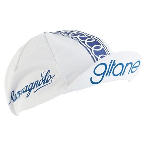 May include: White cycling cap with blue accents and text. The cap features the word "Gitane" on the brim and "Campagnolo" on the side, both in blue script. A blue and white patterned band runs across the top.