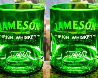 May include: Two green Jameson Irish Whiskey glasses. The glasses have the Jameson logo and "Irish Whiskey" printed on them, along with the year "1780". The glasses are made from recycled glass.