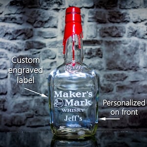 May include: A clear glass bottle with a red top and a custom engraved label. The label says "Maker's Mark Whiskey Jeff's". The bottle is personalized on the front.