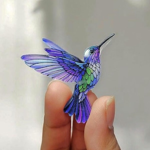 May include: A small, detailed, purple, green, and blue hummingbird figurine.