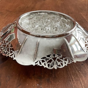 以下が含まれることがあります： 縁が波打っていて、複雑な花柄が施された銀メッキの装飾的なボウル。ボウルの中央部分には、小さな透明なガラスのカップが複数あります。