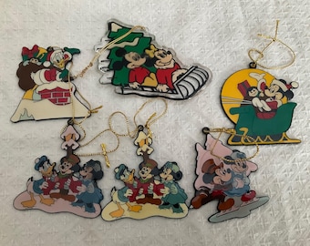 Könnte beinhalten: Satz von zehn Weihnachtsbaumschmuck mit verschiedenen Disney-Charakteren, darunter Mickey Mouse, Minnie Mouse, Donald Duck, Goofy und Pluto. Der Schmuck ist aus Kunststoff und hat eine glänzende Oberfläche. Er ist mit bunter Farbe und Glitzer verziert.