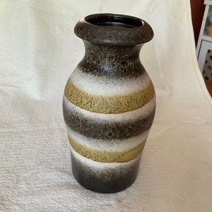 May include: A brown and white ceramic vase with green stripes. The vase has a textured surface and a wide mouth.