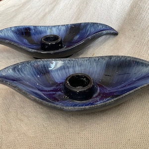 May include: A pair of blue and white ceramic candle holders shaped like leaves. Each holder has a single candle cup in the centre.