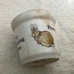 Peut inclure: Une tasse en céramique blanche avec une anse noire et le texte "But First, Coffee" en gras noir. La tasse est posée sur un fond neutre, soulignant son design simple.
