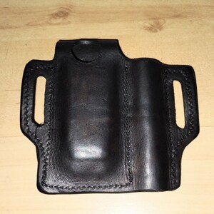 May include: Black leather holster with a stitched design and a cut-out for a small object.