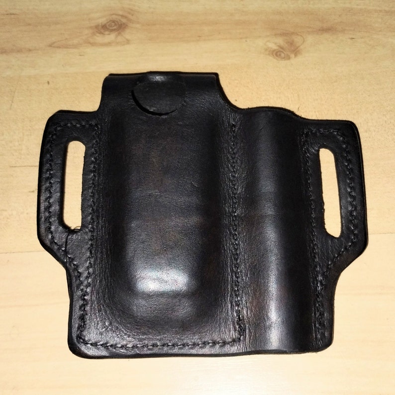 May include: Black leather holster with a stitched design and a cut-out for a small object.