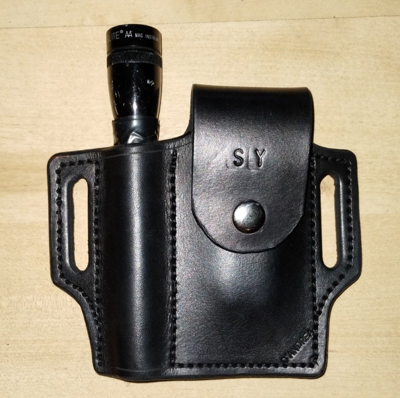 May include: Black leather flashlight holster with a snap closure and a belt loop. The holster is labelled "SLY".